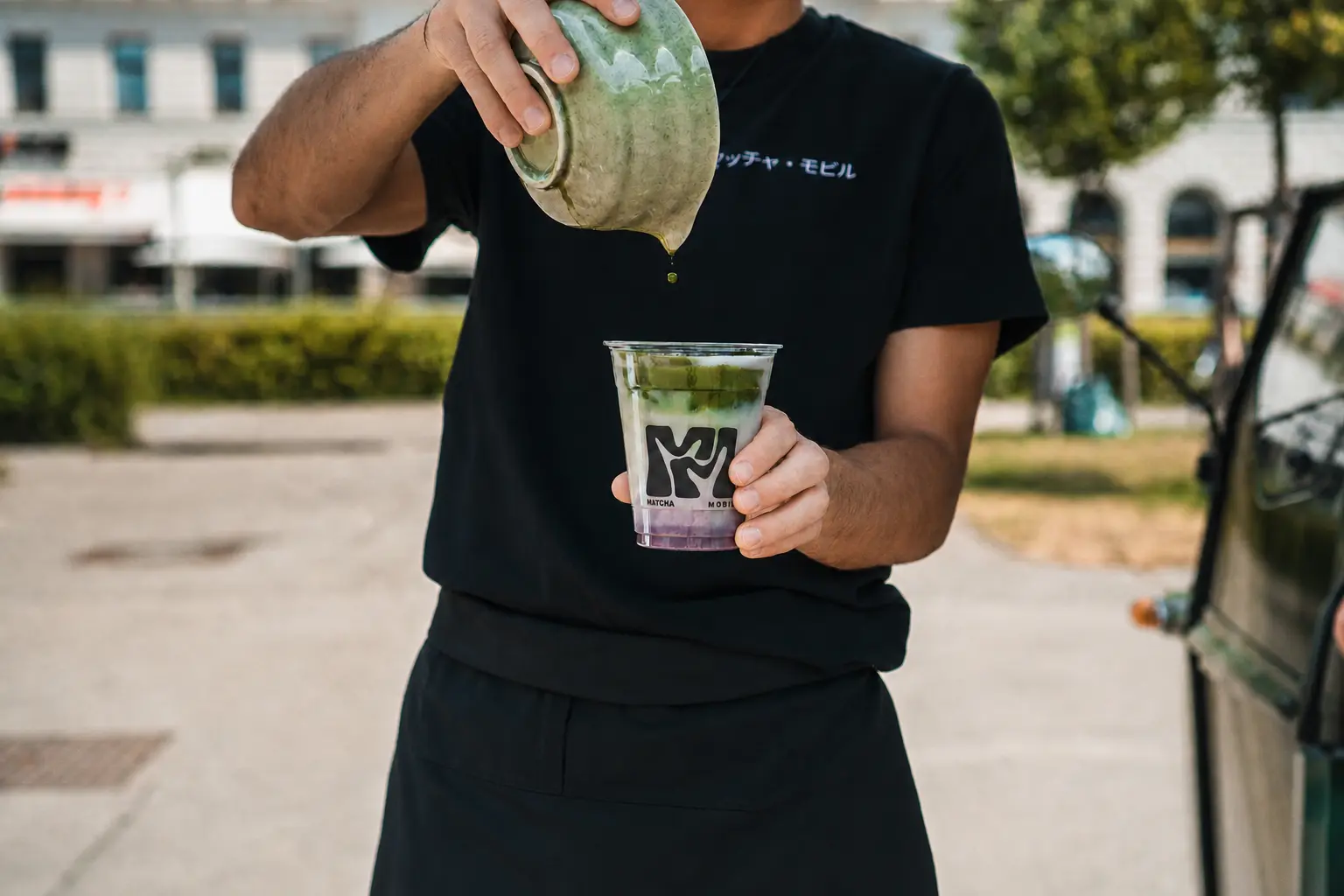 Matcharista gießt Matcha in einen Becher mit MatchaMobil Logo
